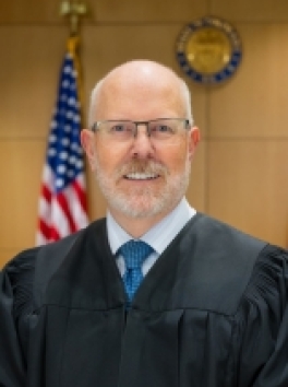 Photo of White Male Judge in front of US Flag and Colorado Court Seal