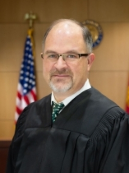 photo of white male Judge in front of US Flag and Colorado State Seal